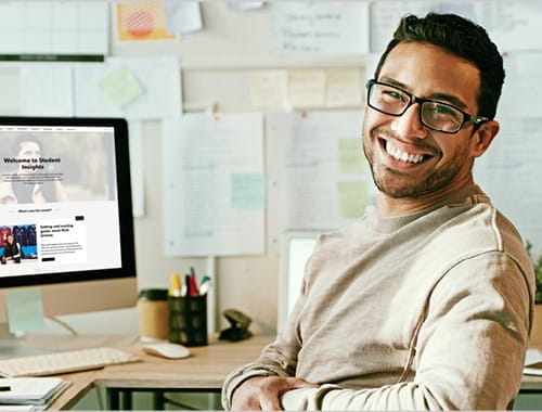 young man glasses office study desk student desktop computer pinboard papers post it notes ICAEW website