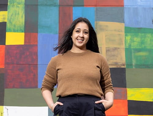 Alina Cummins, Head of Finance at Serpentine, young woman standing in front of wall mural colourful
