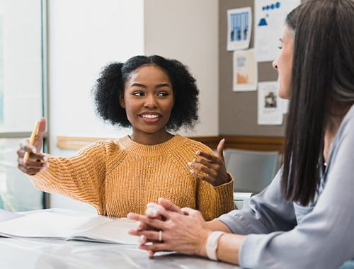 Two young women colleagues office meeting room talking communicating professional language